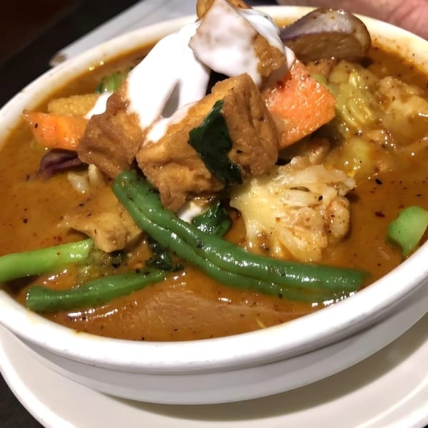 Close-up of a My Thai curry dish with tofu, green beans, carrots, and cauliflower.